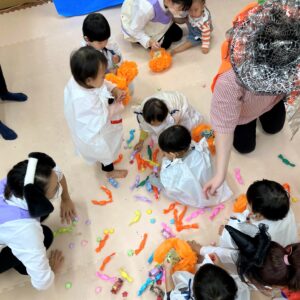 割れたピニャータからお菓子を拾う園児たち