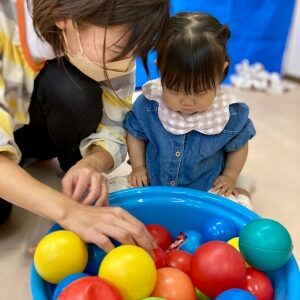 ボールがぎっしり入ったバケツからゼリーを探す子ども