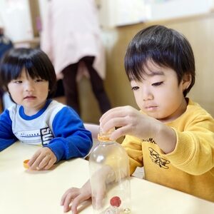 マラカスを製作するお友だちの様子を見つめる子ども