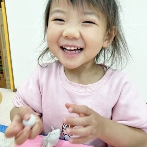 満面の笑顔で粘土遊ぶをする子ども