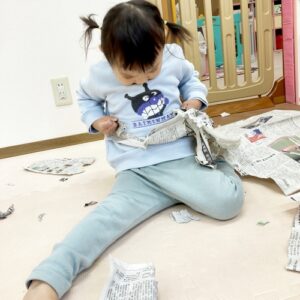 新聞紙を小さく破る子ども