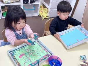 紙の上にビー玉を転がして色をつける子ども