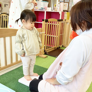 緊張した様子で体重計に乗る子ども