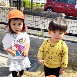 タンポポの花と綿毛を手に持つ子どもたち