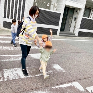 手をあげて横断歩道を渡る子どもと保育士