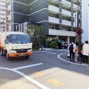 散歩中の園児の横を通り過ぎるゴミ収集車