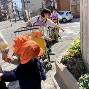 黄色の花を指さす保育士とそれを見ている子どもたち