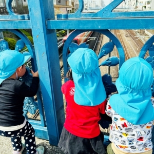 橋の上から電車をみつめる子どもたち