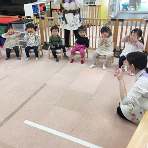 手遊びをする保育士と子どもたち