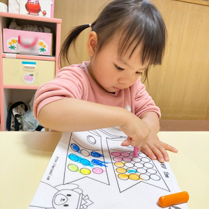 鯉のぼりのに描かれた丸の中にひとつひとつ色を塗る子ども