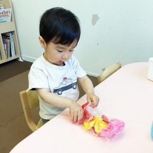 丸めたお花紙を袋に入れて鯉のぼりを作る子ども