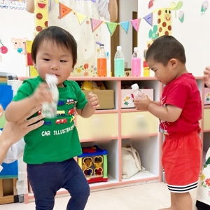 液体の入ったペットボトルを振る子どもたち