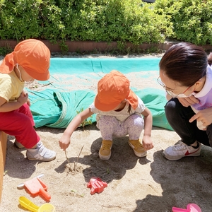 砂場で砂の誕生日ケーキを作る子どもたち