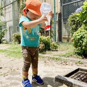 容器に入った水を勢いよく出す子ども