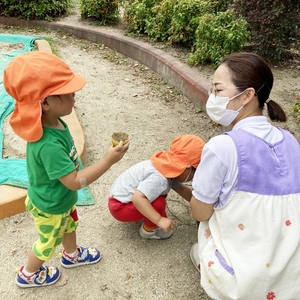 砂遊びをする子どもたちと保育士