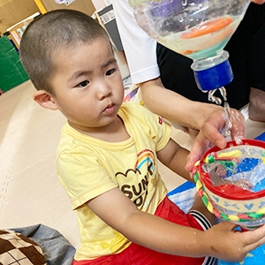 ペットボトルで作った容器に水をためる子ども