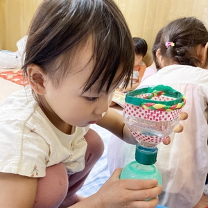 真剣な表情で水を別の容器に移す子ども