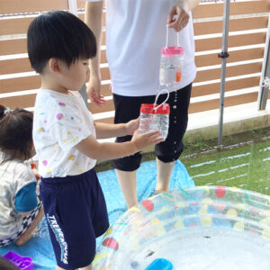 ペットボトルで作った容器に水を入れる子ども