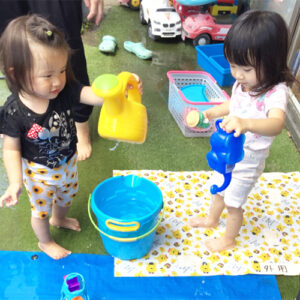 バケツやジョーロで水遊びをする子どもたち