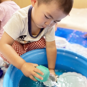 真剣な表情で水を汲んで遊ぶ子ども