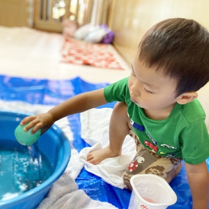 容器に水を汲んで遊ぶ子ども