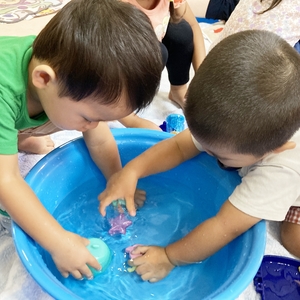 タライに貯めた水で遊ぶ子どもたち