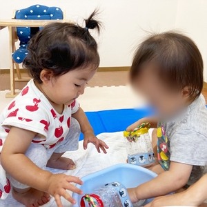 お友だちと向かい合って夢中で水遊びをする子ども