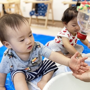 容器から流れる水を触る子ども