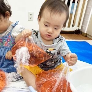 真剣な表情で色水入りの袋を触る子ども