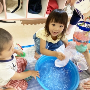 空き容器に水を入れて遊ぶ子ども