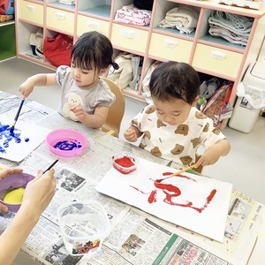 筆に絵の具をつけて色を塗る子どもたち