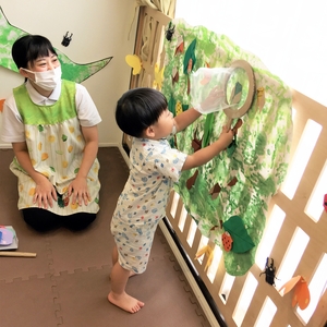 虫捕り遊びをする子どもと見守る保育士