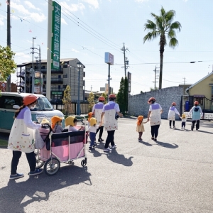 先生と手を繋いだり避難車に乗って避難する子どもたち