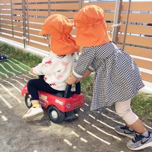 園庭でお友だちが乗る車を押す子ども