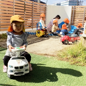 園庭で車に乗る子どもたち