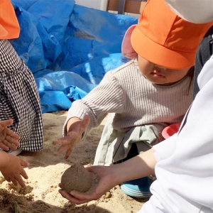 砂場でだんごを作る子どもたち