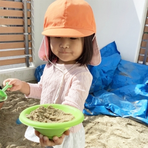 砂を入れた器を持つ子ども