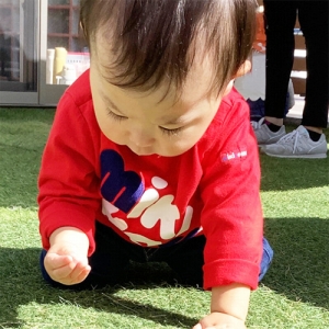 地面に座って芝生を触る子ども