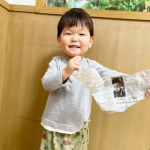 新聞紙を破って笑顔を見せる子ども