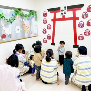 鳥居の前で神主役をする子どもとお願いをするみんな