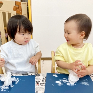 布につけた白い絵の具を画用紙につける子ども