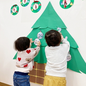 クリスマスツリーに飾りをつける子どもたち