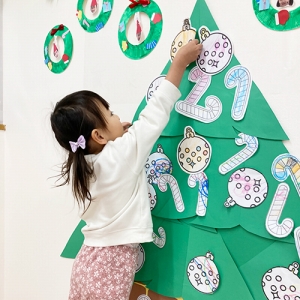 クリスマスツリーに飾りをつける子ども