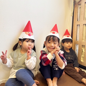 サンタクロースが描かれた三角帽子を被って笑顔を見せる子どもたち