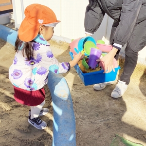 砂場遊びの片付けをする子ども