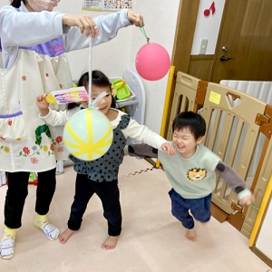 風船を羽子板で叩いて遊ぶ子どもたち