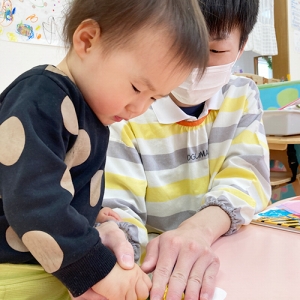 節分の鬼の壁面飾りを作る子どもと保育士