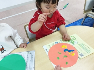 気球の風船の部分にスプーンで絵具を着彩する子ども