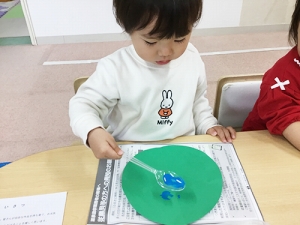 気球の風船の部分にスプーンで絵具を着彩する子ども