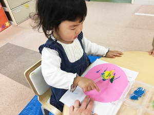 気球の風船の部分にスプーンで絵具を着彩する子ども